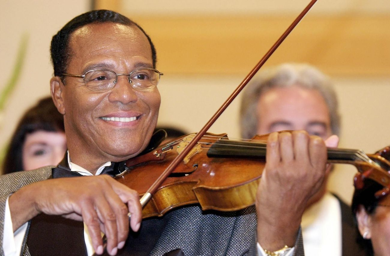 Louis Farrakhan poses with a violin at a press conference in 2002